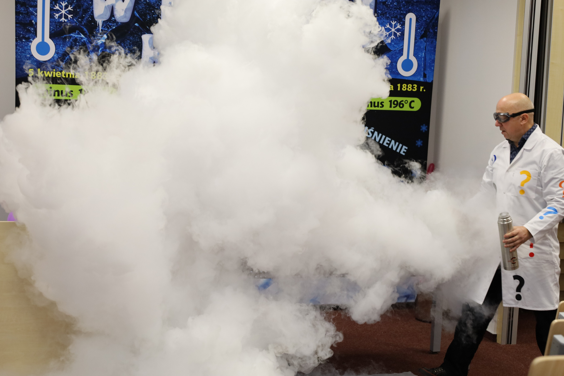 Eksperyment naukowy z dużą ilością białego dymu. Na zdjęciu mężczyzna przeprowadzający pokaz.