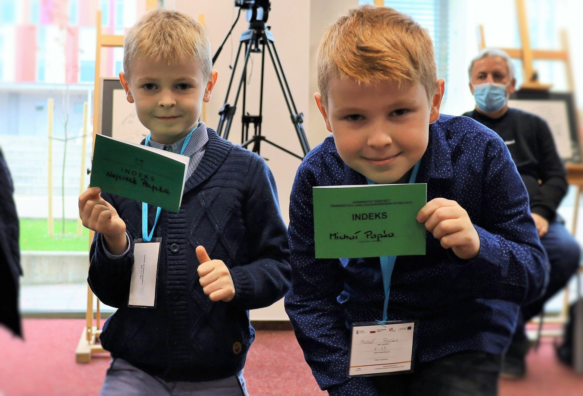 Dwaj chłopcy pozują do zdjęcia, trzymając w rękach indeksy.