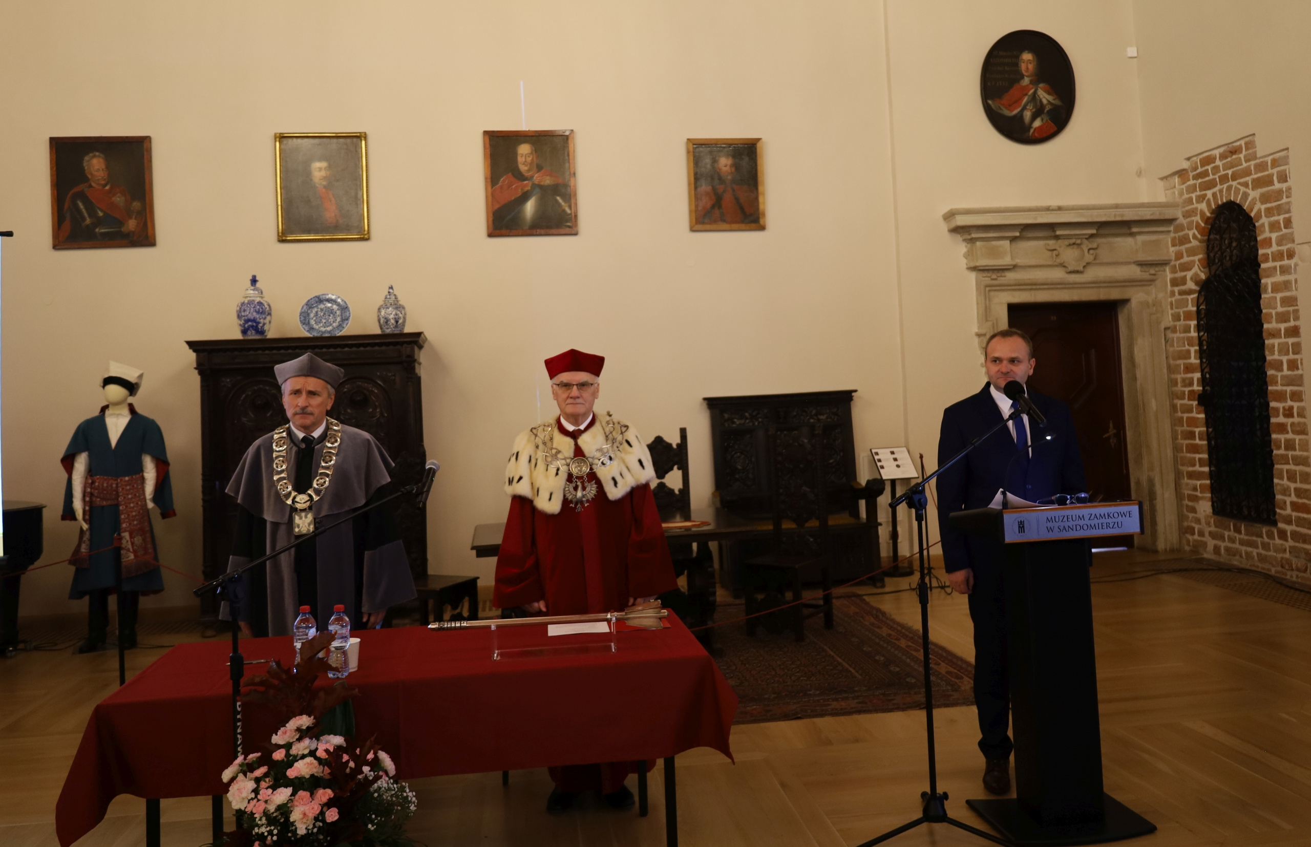 Uroczystość odbyła się w Sali Rycerskiej sandomierskiego zamku. W tle widoczne zabytkowe rekwizyty. Na pierwszym planie władze rektorskie i dziekańskie.