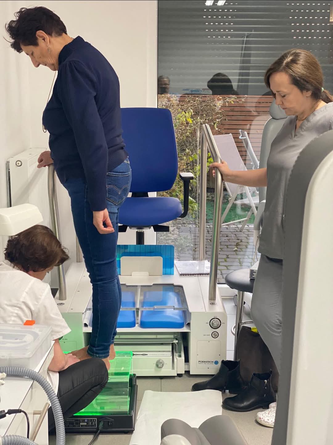 Na zięciu widać Kobietę która poddawana jest badaniu na podoskopie. Obok stoi przedstawicielka UJK w Kielcach, a przedstawicielka firmy szkoleniowej dokonuje odczytu. 