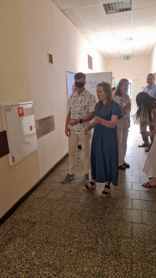 Na zdjęciu widoczny jest korytarz Uczelni oraz grupa uczestników szkolenia. 